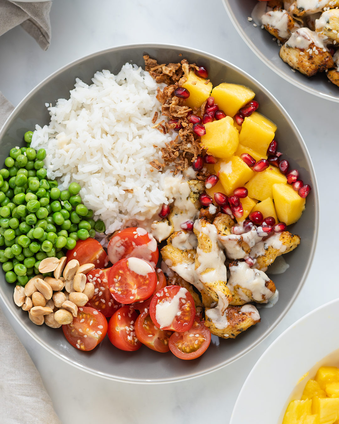 Poke Bowl de arroz basmati con pollo, mango, granada, tomates cherry y cebolla frita