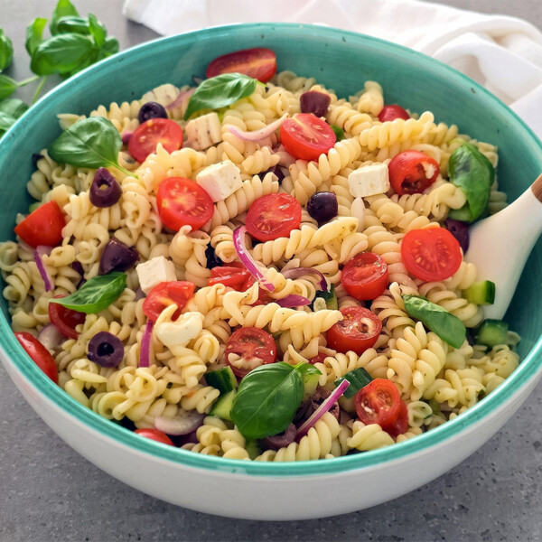 Ensalada de pasta griega con queso feta, aceitunas, tomates cherry, pepino y cebolla